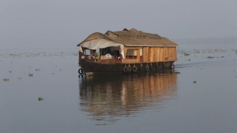 Houseboat cruising through backwater stretch in Kumarakom