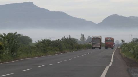 Trucks on road with a mountain background