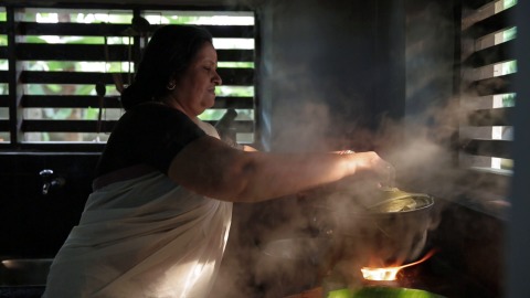 Woman preparing Onam ada in woodfire kitchen